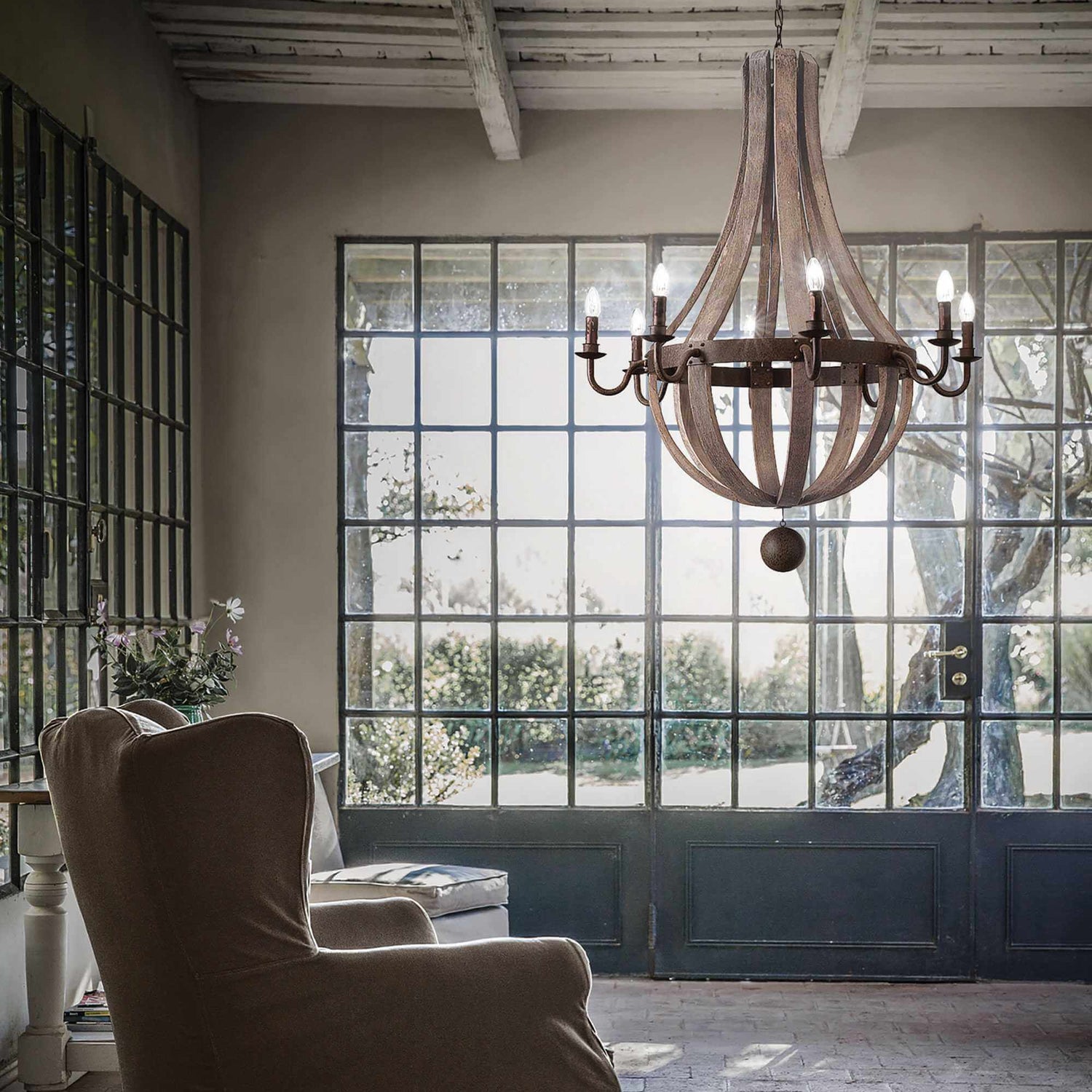 8 light wooden and metal chandelier in sitting room with large window and chair