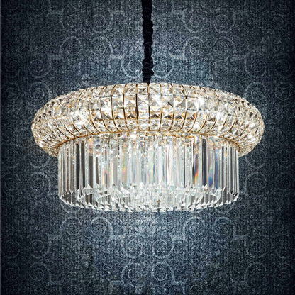 Drum shaped golden chandelier with square and round crystals on a dark blue patterned background